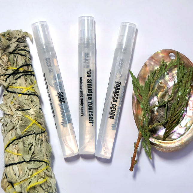 Three small perfume sprays are shown against a white background. There is real sage and cedar to the left and right of the three bottles.