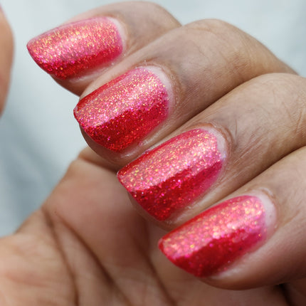 Close-up of a hand with red glittery nail polish on a blurred background