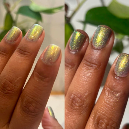 Two hands with glittery gold nail polish against a blurred green leaf background