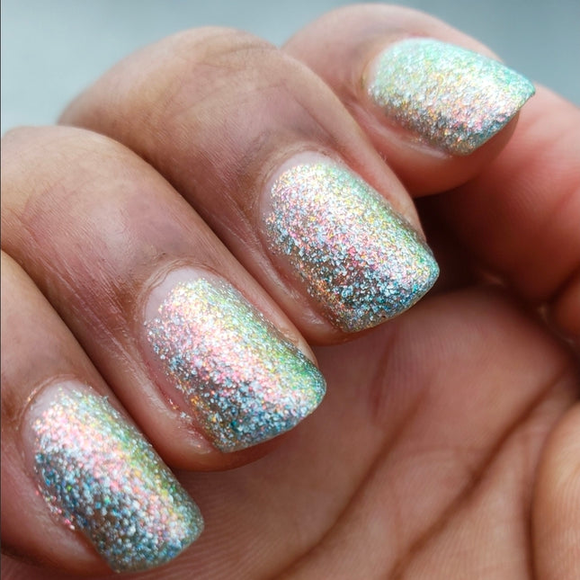Close-up of a hand with glittery nail polish on a neutral background