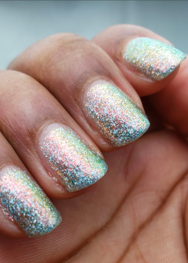 Close-up of a hand with glittery nail polish on a neutral background